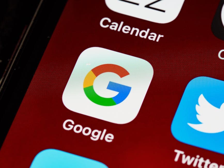 Macro view of a smartphone displaying Google and other app icons on the home screen.